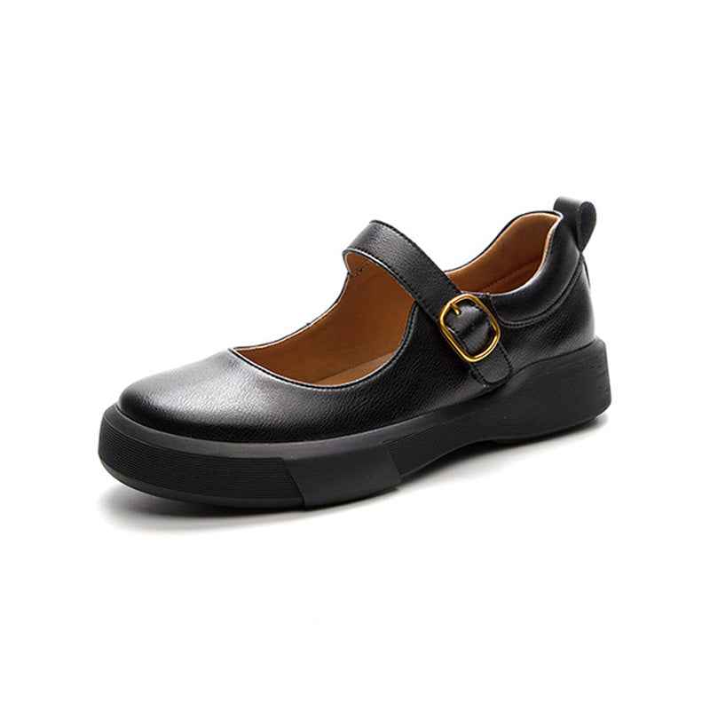 A single black cow leather Mary-Jane shoe with a thick sole and a gold buckle detail. The shoe has a round toe, set against a white background. 