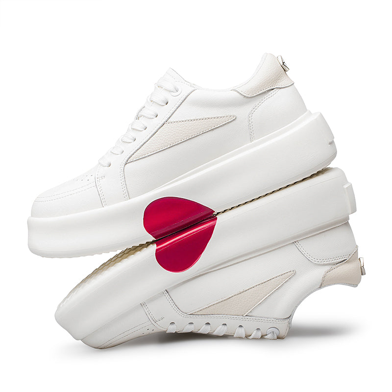 Pair of white thick-soled platform sneakers with a prominent red heart design on one shoe